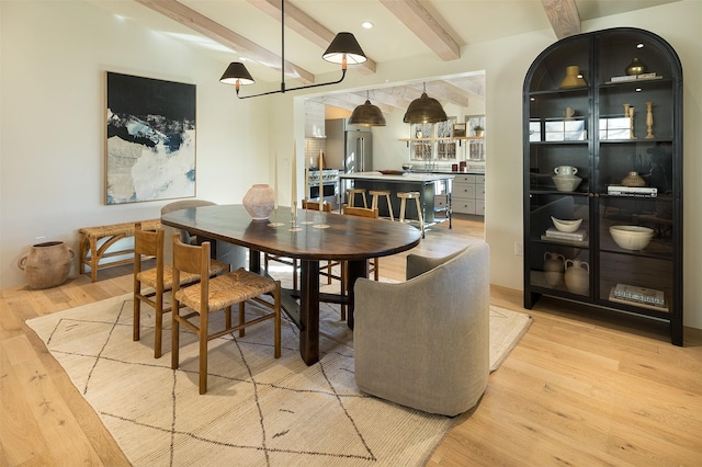 dining space featuring beam ceiling and light wood-type flooring