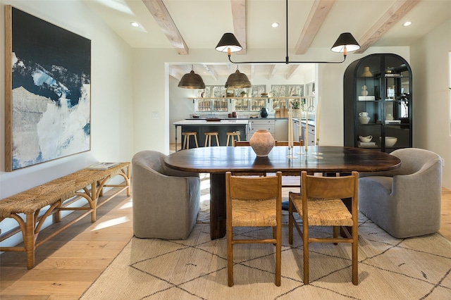 dining area with beam ceiling and light hardwood / wood-style floors