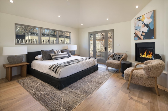 bedroom featuring access to exterior, light wood-type flooring, and lofted ceiling