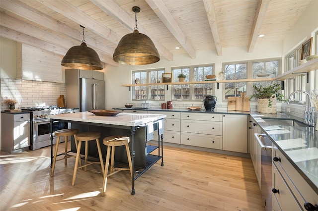 kitchen featuring sink, a breakfast bar area, dark stone countertops, high quality appliances, and pendant lighting