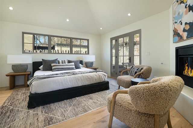 bedroom featuring access to outside, lofted ceiling, and light wood-type flooring