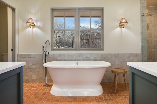 bathroom featuring a washtub, vanity, tile patterned floors, and tile walls