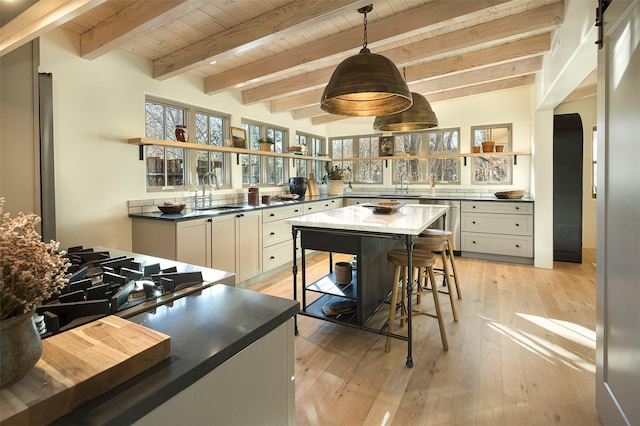 kitchen with wood ceiling, sink, decorative light fixtures, light hardwood / wood-style flooring, and beamed ceiling