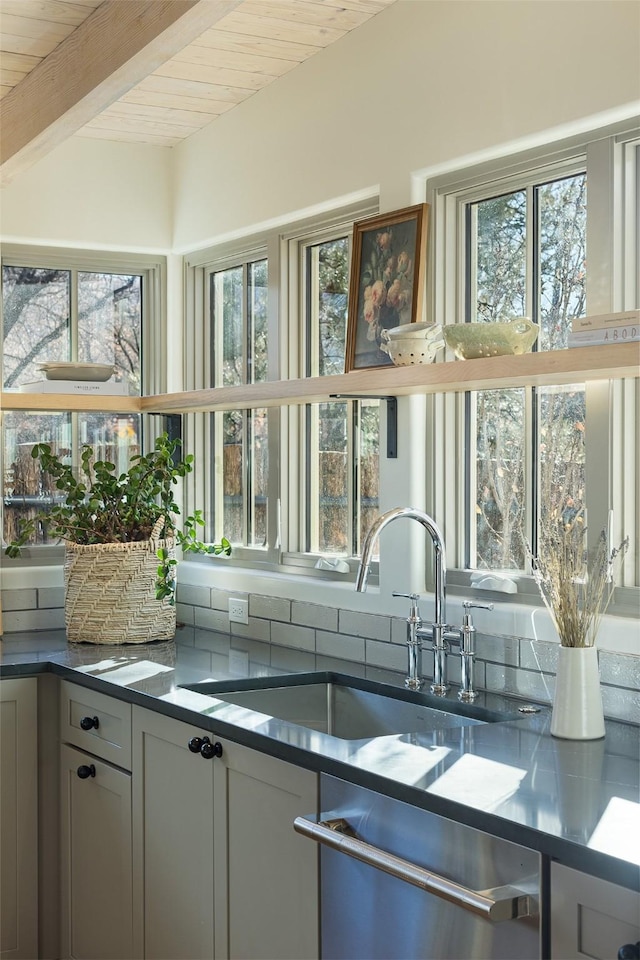 kitchen featuring beamed ceiling, sink, stainless steel dishwasher, and wood ceiling