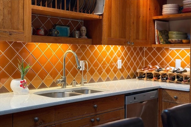 kitchen featuring light stone countertops, dishwasher, backsplash, and sink