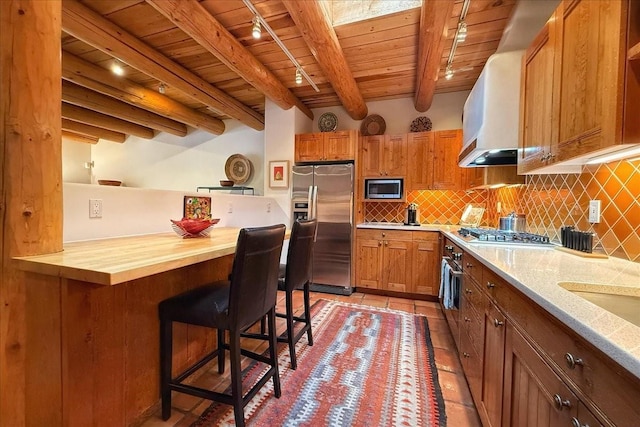 kitchen with light tile patterned floors, wood ceiling, beam ceiling, butcher block countertops, and appliances with stainless steel finishes