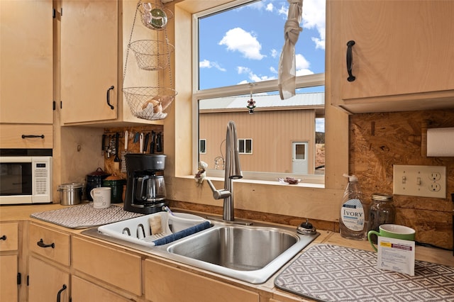 kitchen featuring light brown cabinetry, decorative backsplash, and sink