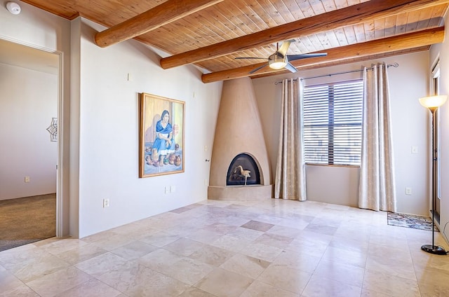 unfurnished living room featuring a ceiling fan, wooden ceiling, a fireplace, and beam ceiling