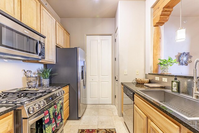 kitchen with sink, light brown cabinets, hanging light fixtures, dark stone counters, and appliances with stainless steel finishes