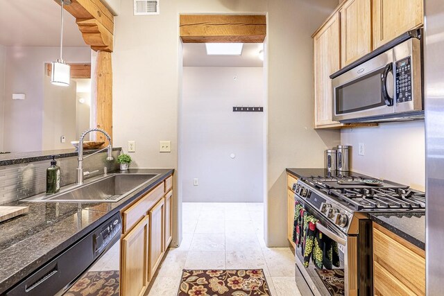 kitchen with dark stone countertops, hanging light fixtures, and stainless steel appliances