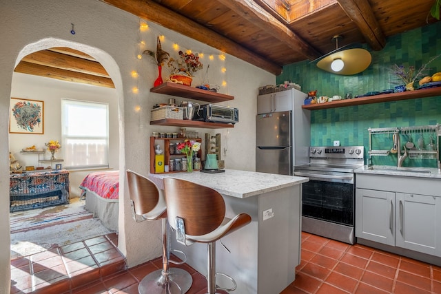 kitchen featuring beam ceiling, sink, a kitchen breakfast bar, and appliances with stainless steel finishes