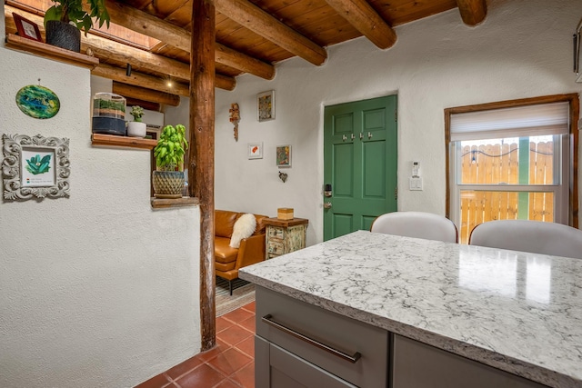 kitchen with gray cabinetry, beam ceiling, wooden ceiling, and dark tile patterned floors