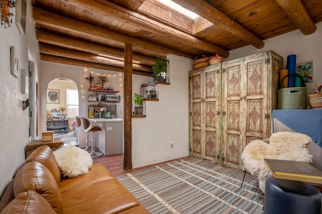 tiled living room featuring beam ceiling, a skylight, and wooden ceiling