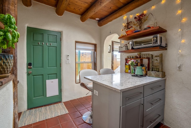 kitchen featuring beamed ceiling, gray cabinets, wood ceiling, and dark tile patterned floors