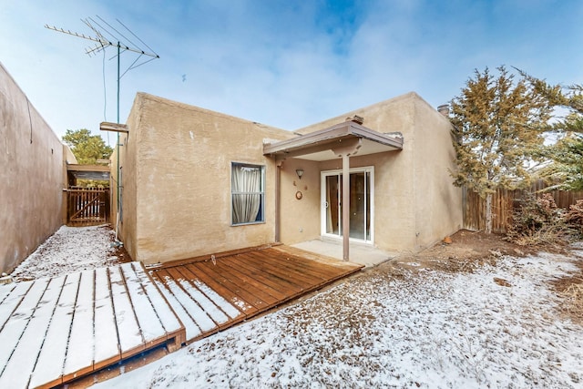 snow covered rear of property with a deck