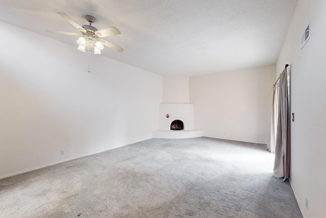 unfurnished living room featuring ceiling fan, a fireplace, and carpet floors