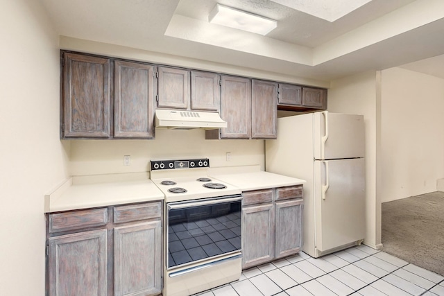 kitchen with a raised ceiling, light tile patterned floors, and white appliances