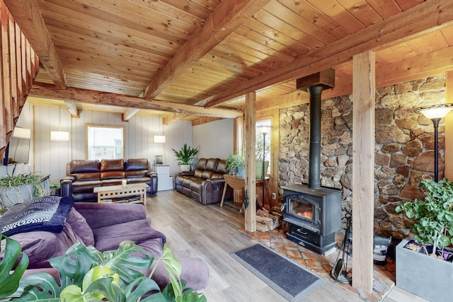 living room with beamed ceiling, wooden ceiling, a wood stove, and a healthy amount of sunlight