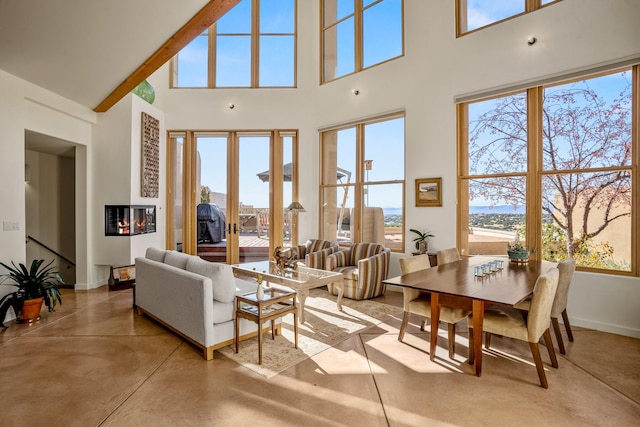 living room with a high ceiling, beam ceiling, and a healthy amount of sunlight