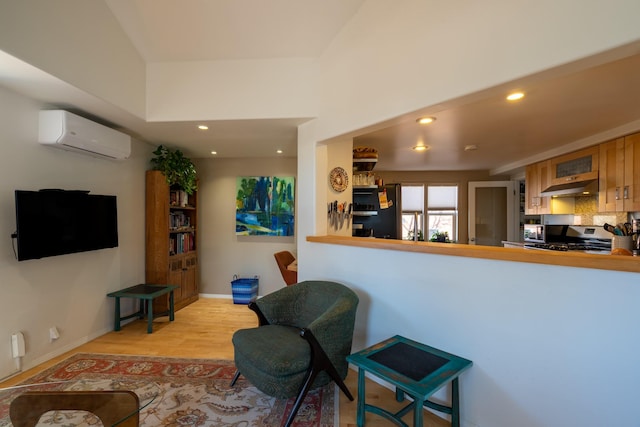 living room with a wall unit AC and light hardwood / wood-style flooring