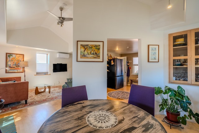 dining room featuring ceiling fan, light hardwood / wood-style flooring, a wall mounted air conditioner, and vaulted ceiling