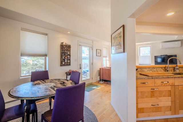 dining area with baseboard heating, light hardwood / wood-style flooring, and a wall unit AC