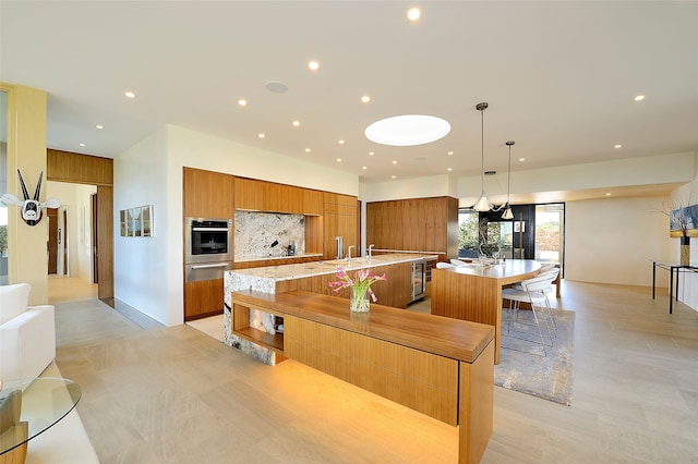 kitchen with pendant lighting, a spacious island, oven, backsplash, and a breakfast bar area