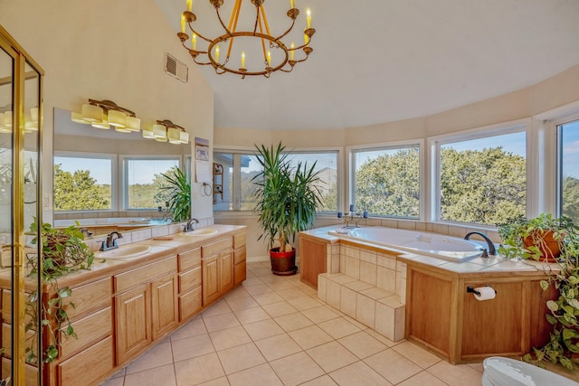 bathroom featuring vanity, tile patterned flooring, an inviting chandelier, and tiled tub