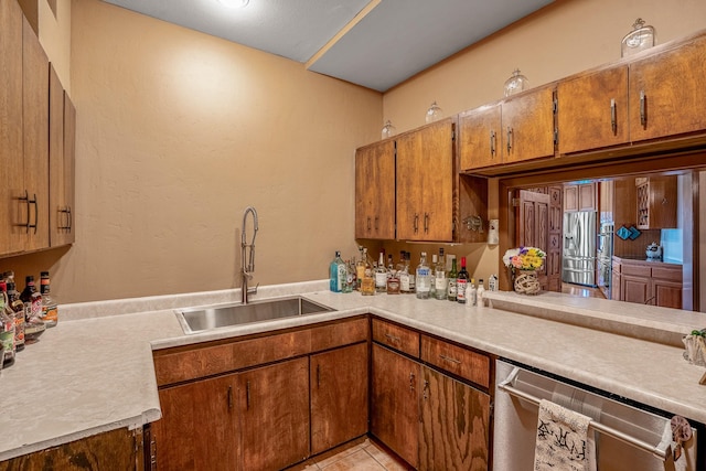 kitchen with kitchen peninsula, appliances with stainless steel finishes, light tile patterned flooring, and sink