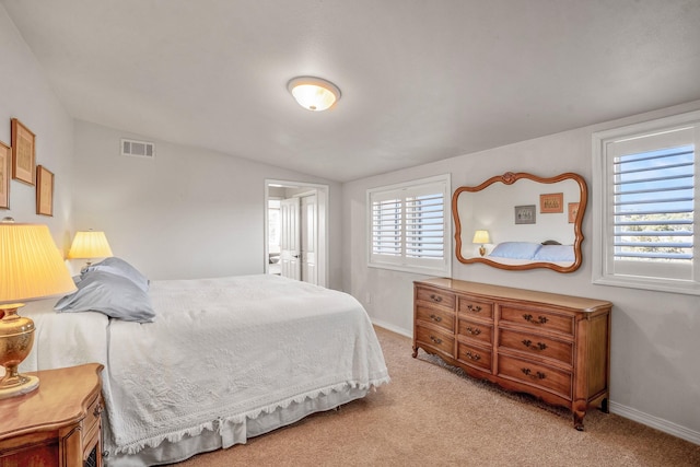 bedroom featuring lofted ceiling, light colored carpet, and multiple windows