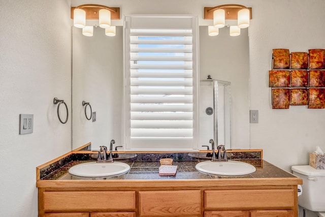 bathroom with a shower with shower door, vanity, and toilet