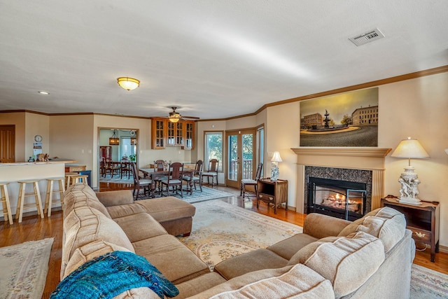 living room with hardwood / wood-style floors, ceiling fan, and ornamental molding