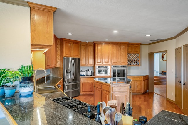 kitchen with light hardwood / wood-style floors, stainless steel fridge with ice dispenser, a center island, ornamental molding, and sink