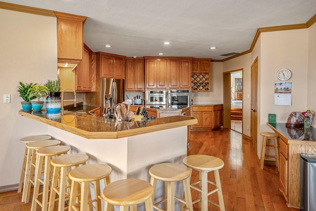 kitchen featuring kitchen peninsula, stainless steel fridge with ice dispenser, dark hardwood / wood-style floors, and a kitchen bar