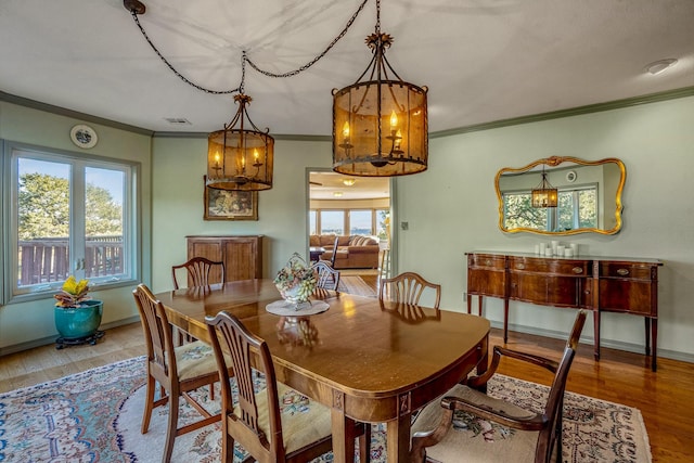 dining space with ornamental molding, a notable chandelier, and hardwood / wood-style flooring