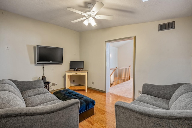 living room featuring a skylight, a textured ceiling, light wood-type flooring, and ceiling fan