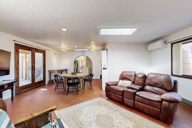 living room with an AC wall unit, french doors, a skylight, and a textured ceiling