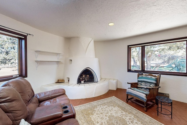 living room with a textured ceiling, hardwood / wood-style floors, and a tiled fireplace