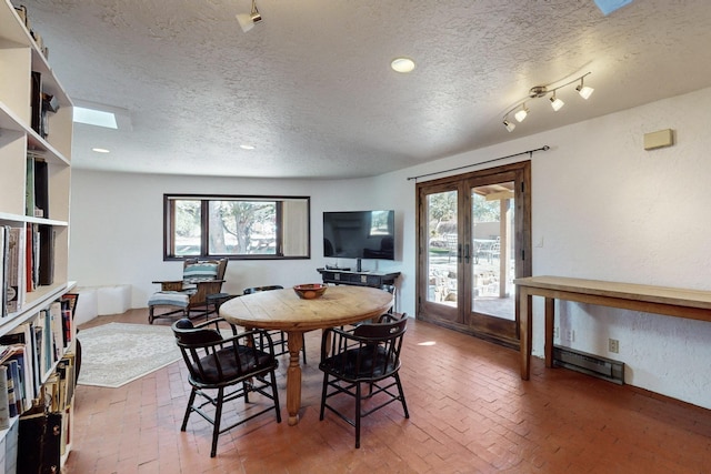 dining room featuring a textured ceiling, french doors, and a healthy amount of sunlight