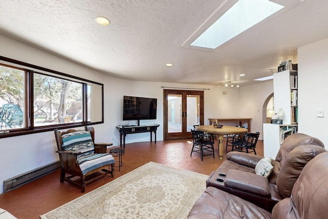 living room featuring baseboard heating, a textured ceiling, and a skylight