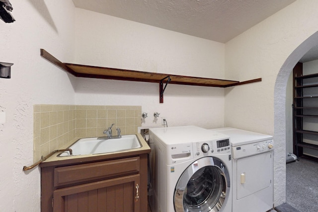 washroom with sink, a textured ceiling, carpet, hookup for a washing machine, and cabinets