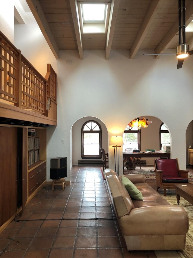 living room with beam ceiling, wood ceiling, a towering ceiling, and a chandelier