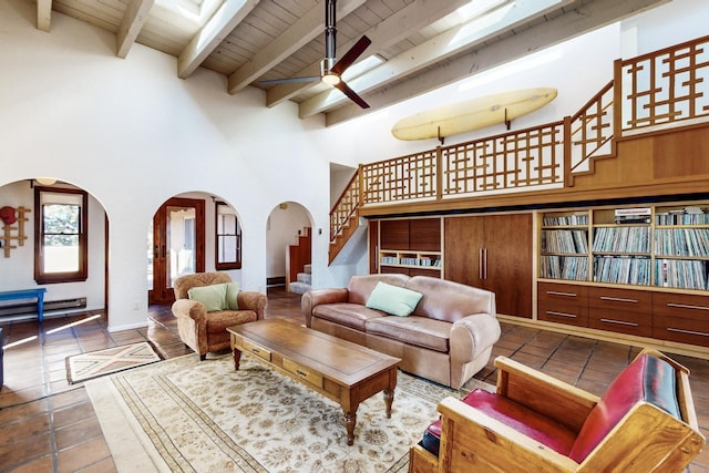 living room with beam ceiling, ceiling fan, wooden ceiling, and a high ceiling