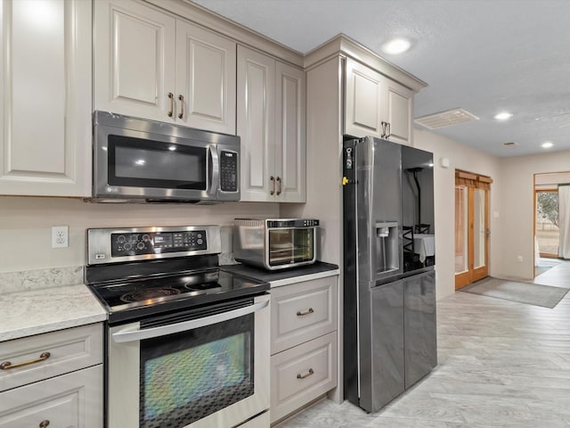 kitchen featuring stainless steel appliances, gray cabinetry, and light stone countertops