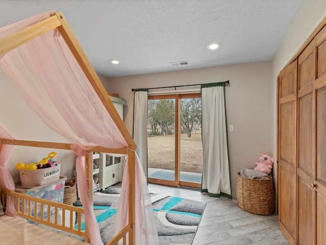 bedroom with a textured ceiling, light hardwood / wood-style flooring, and access to exterior