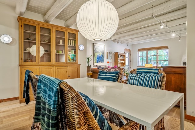 dining room featuring track lighting, beam ceiling, light hardwood / wood-style floors, and wood ceiling