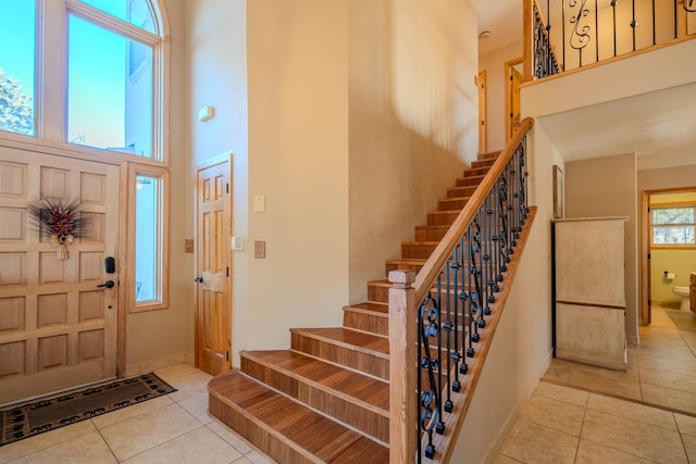 entryway with light tile patterned flooring and a high ceiling