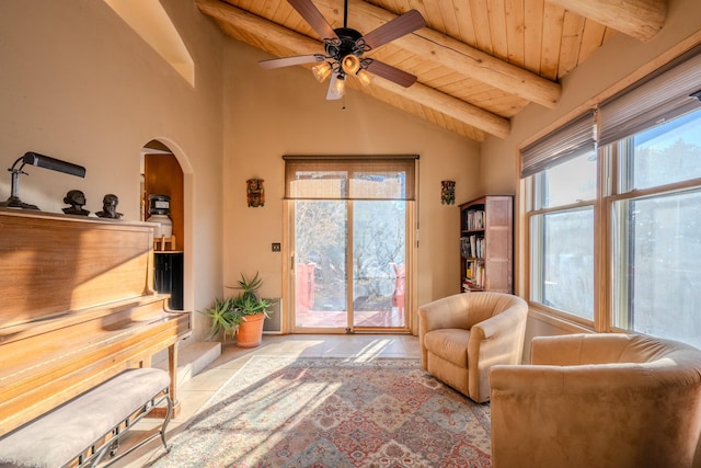 living area with vaulted ceiling with beams, ceiling fan, arched walkways, wooden ceiling, and tile patterned flooring