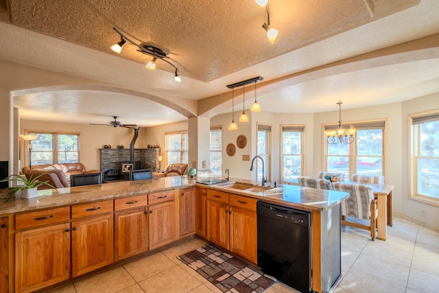 kitchen featuring dishwasher, brown cabinets, open floor plan, a wood stove, and a sink