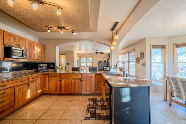 dining space featuring sink, a wood stove, a textured ceiling, and light tile patterned floors